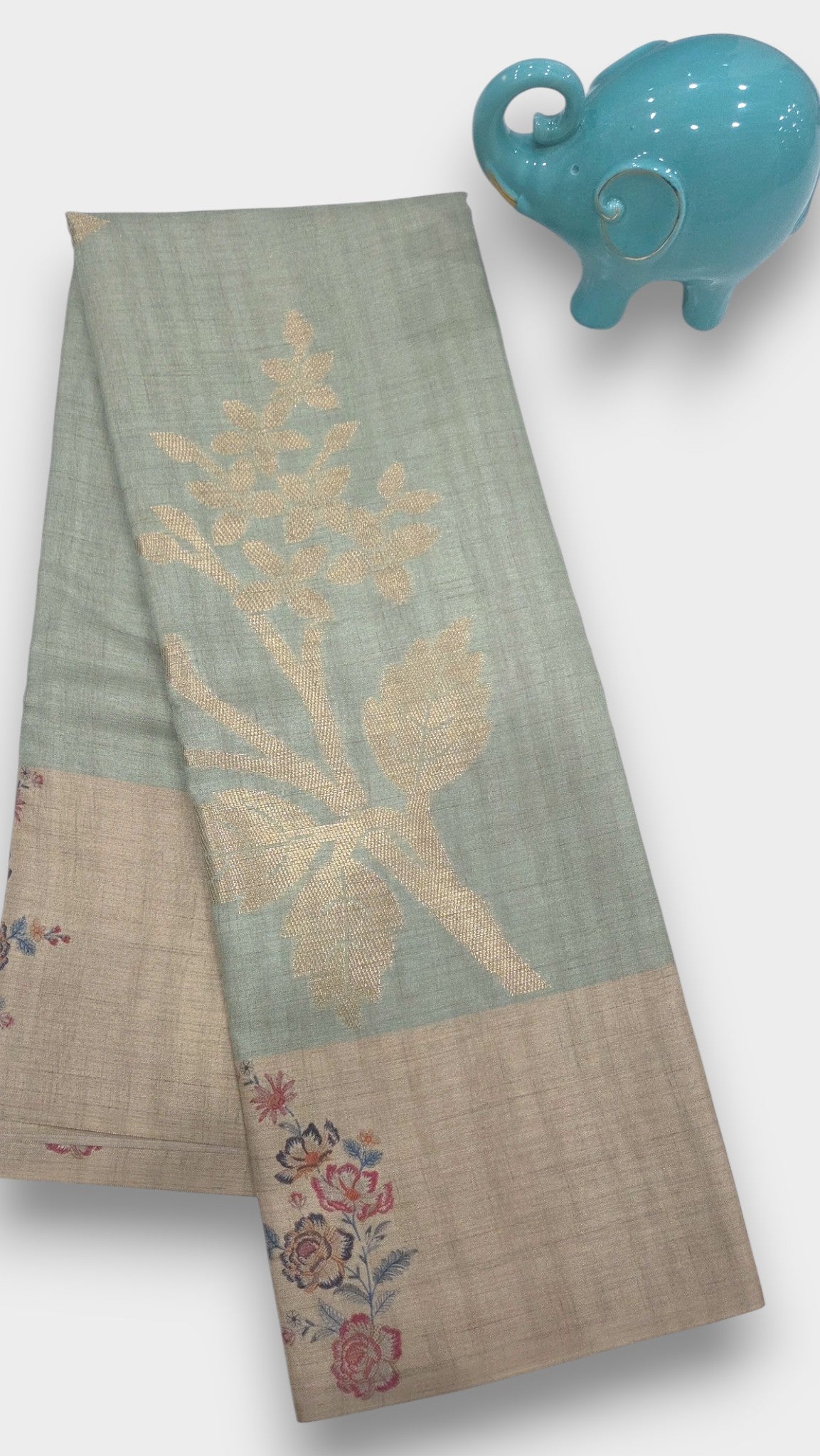 Handcrafted silk saree with floral embroidery from Mayurikaa Silk and Sarees, next to a blue ceramic elephant.